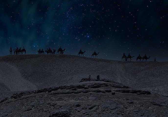 Silhouettes of camels and riders crossing the Atacama Desert under a star‑filled night sky