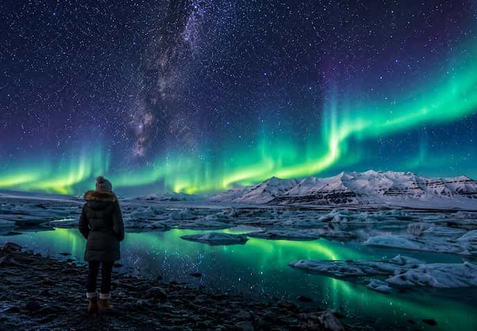 Northern Lights (Aurora Borealis) glowing over Icelandic snowy landscape under a star-filled night sky