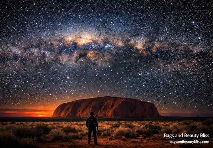 Traveler gazing at the Milky Way above Uluru in Australia's desert night sky, cinematic travel photography evoking wonder and reflection. Uluru Stargazing – Australia’s Desert Night Sky Experience