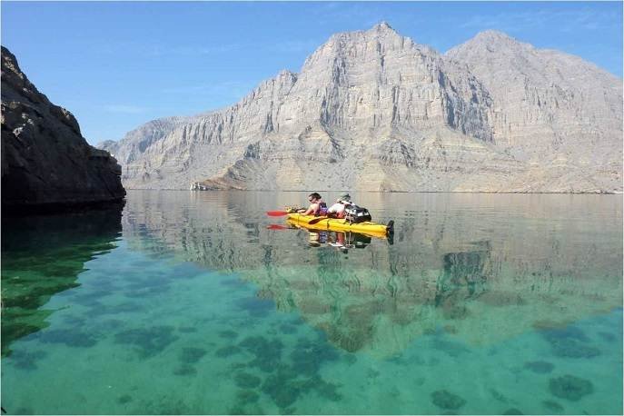 Kayakers explore the calm turquoise waters of the Musandam Fjords in Oman.