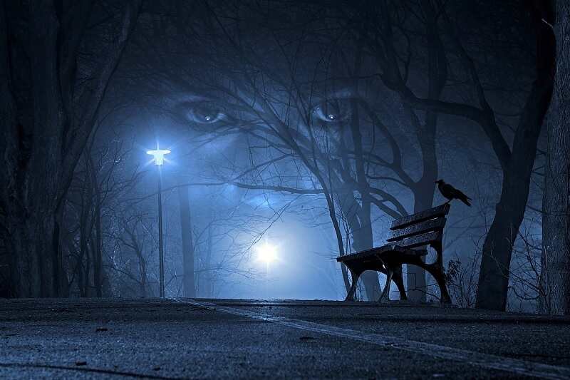 Foggy park with ghostly face in the sky during rainy Halloween night in the UK.