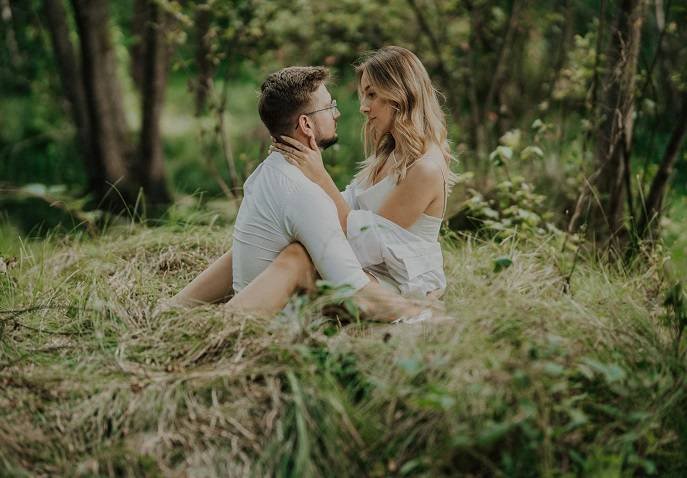 A couple sitting closely in tall grass, enjoying a peaceful Valentine’s Day nature retreat