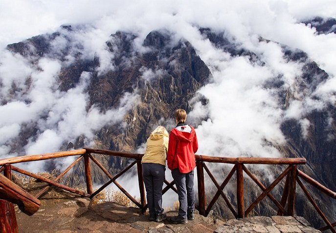A couple on a cliff, admiring mountains covered by fog.