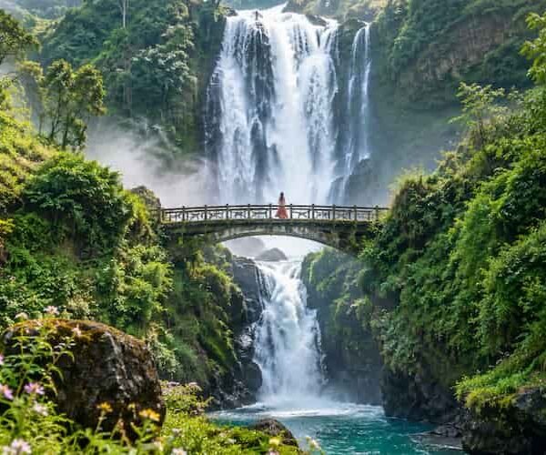 Woman on a bridge overlooking a waterfall during a peaceful digital detox travel escape